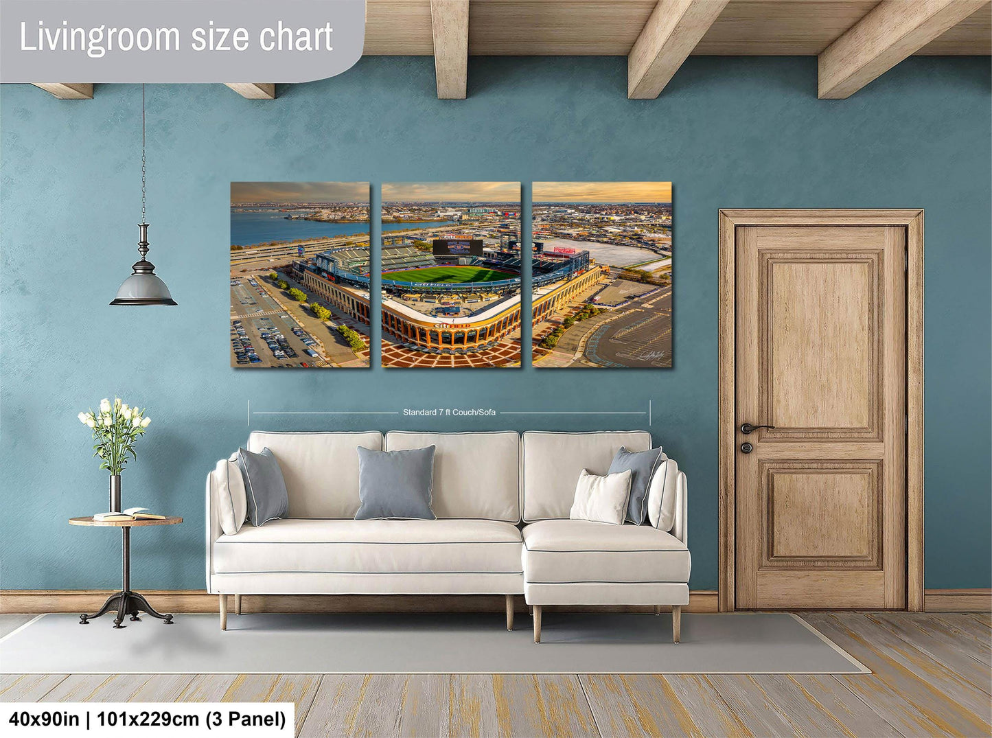 The image is a living room with a large wall art depicting a baseball stadium. The wall art is divided into three panels, each showing different aspects of the stadium. The living room has a white sofa and a wooden door, and the floor is covered with a gray rug.