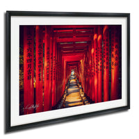 A framed photograph depicting a long, narrow path lined with red torii gates, creating a striking and visually captivating scene.