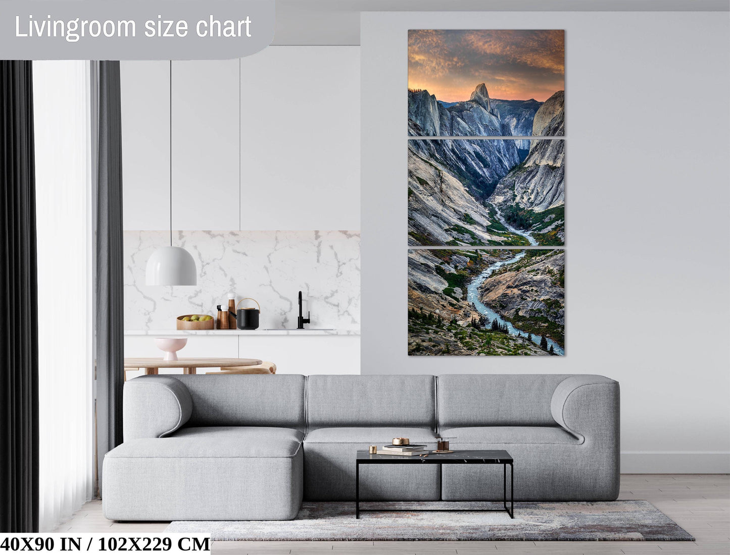 The image is a living room with a gray sofa and a coffee table in front of it. Above the sofa, there is a large painting depicting a scenic mountain landscape with a winding river. The painting is framed and hangs on the wall, adding a touch of nature and artistry to the room.