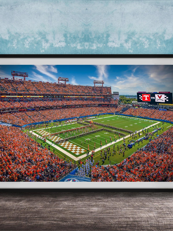 A framed photograph of a crowded football stadium during a game, with the field and stands filled with spectators.