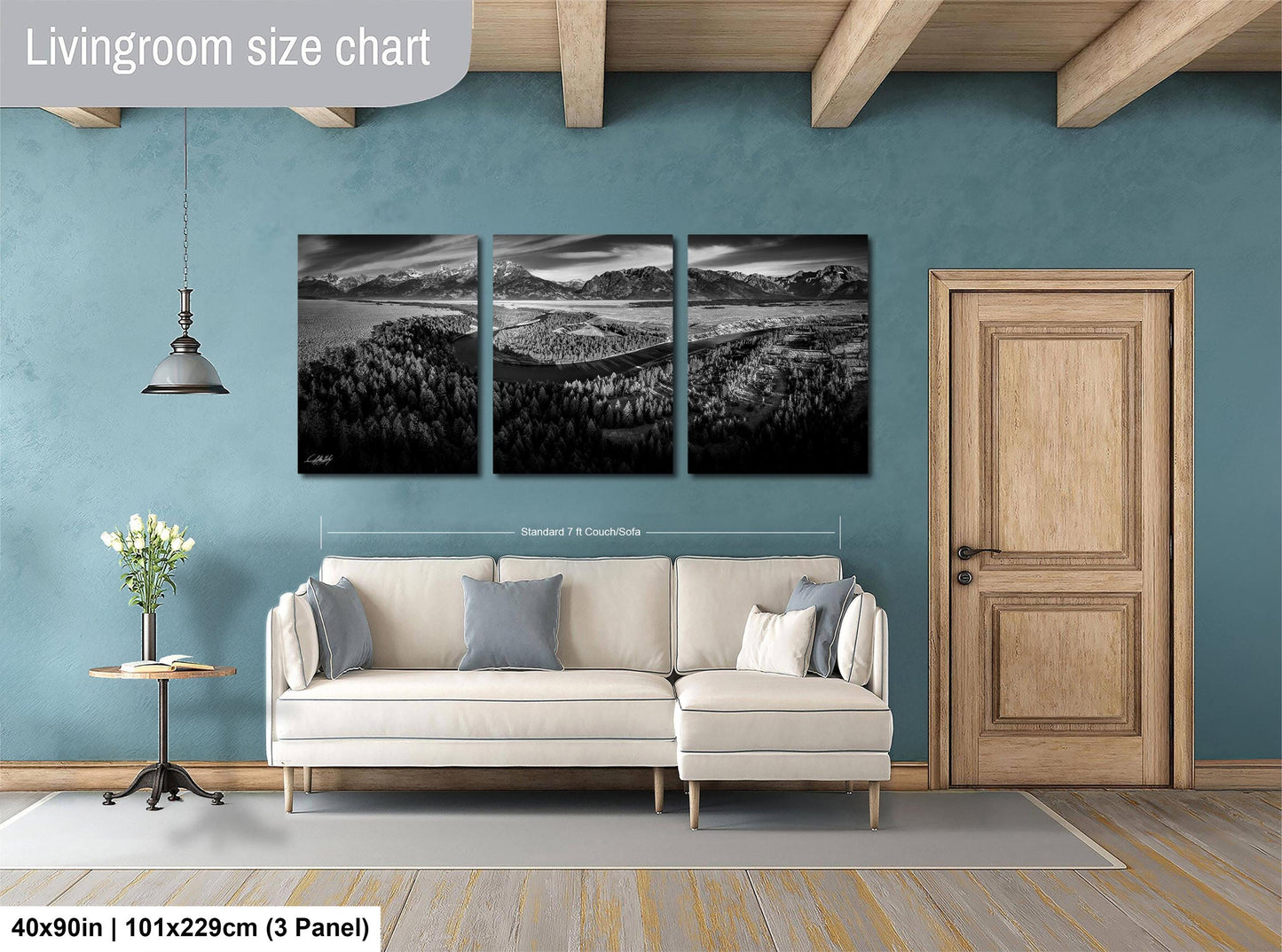 The image is a living room with a white sofa, a wooden door, and a large wall art depicting a landscape scene.