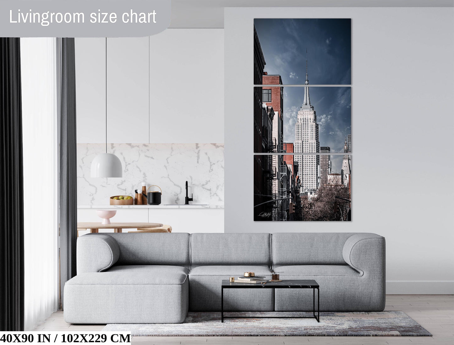 The image is a living room with a gray sofa, a coffee table, and a large wall art depicting the Empire State Building.