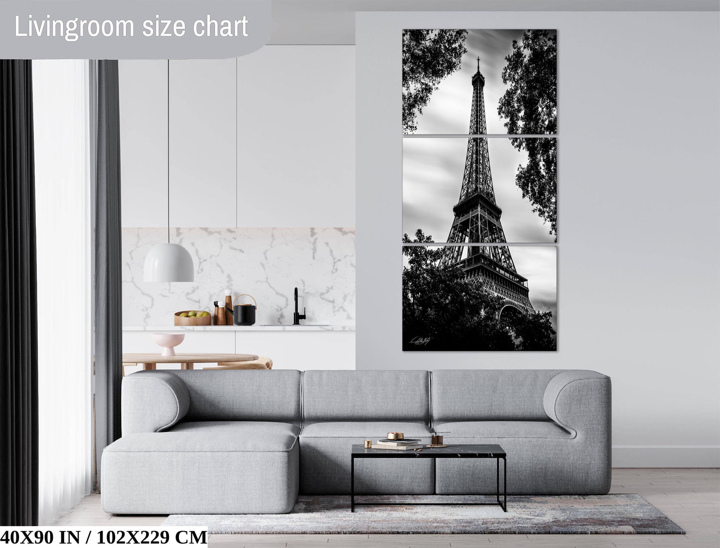 The image is a living room with a gray sofa, a coffee table, and a large black and white photograph of the Eiffel Tower on the wall.
