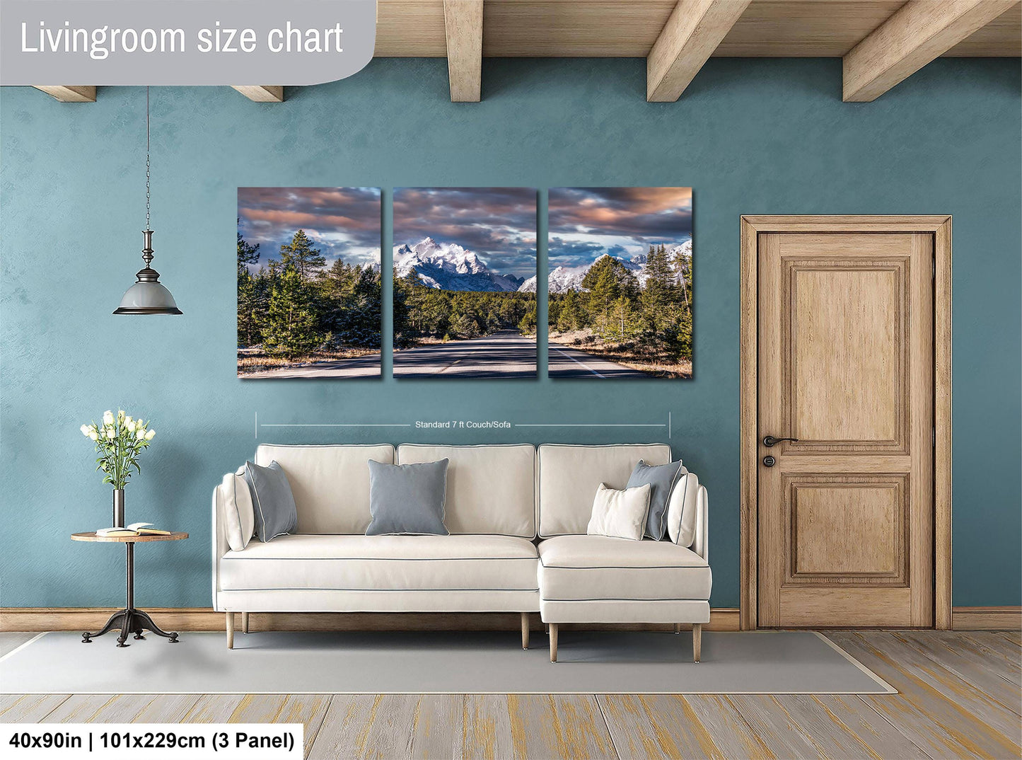 The image is a living room with a large wall art depicting a scenic mountain landscape. The wall art is divided into three panels, each showing a different part of the mountain range. The living room has a white sofa and a wooden door, creating a cozy and inviting atmosphere.