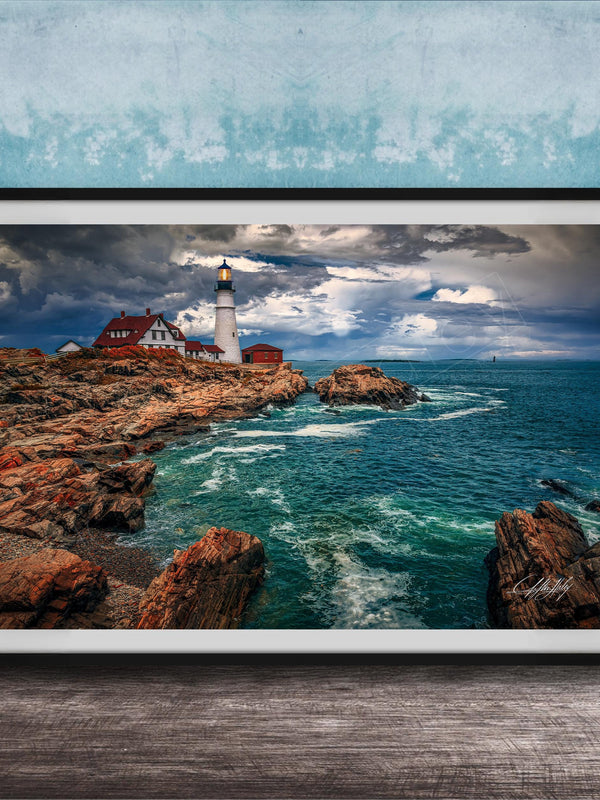 A framed photograph of a lighthouse on a rocky coastline, with the ocean and cloudy sky visible in the background.