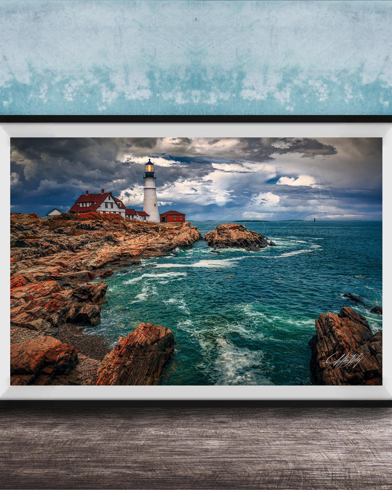 A framed photograph of a lighthouse on a rocky coastline, with the ocean and cloudy sky visible in the background.