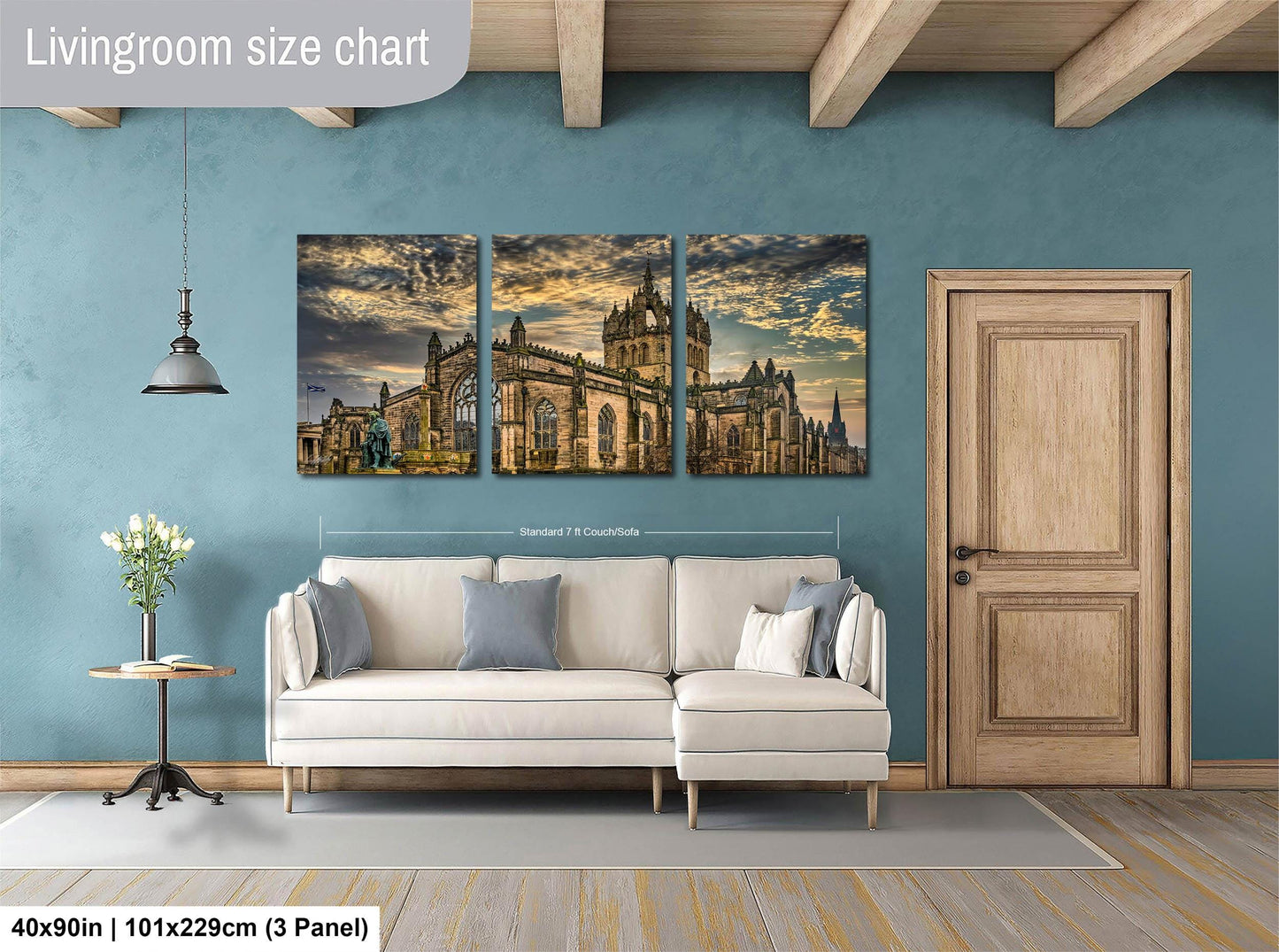 The image is a living room with a large white sofa and a wooden door. Above the sofa, there is a wall-mounted painting depicting a castle or palace-like structure. The painting is divided into three panels, each showing different parts of the building. The wall has a blue color, and there is a wooden beam ceiling.