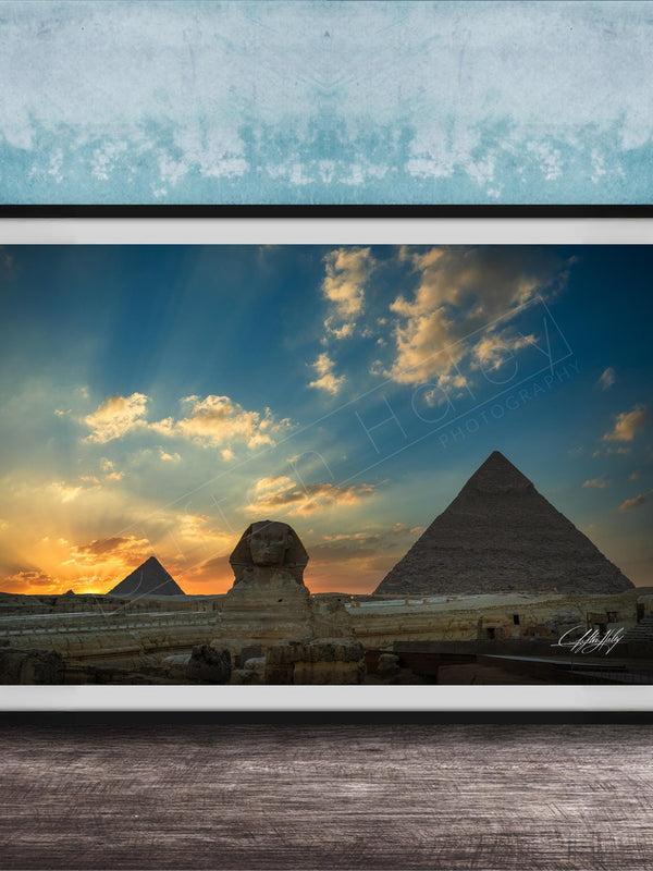 the Great Pyramids of Giza against a stunning sunset sky, with the Sphinx in the foreground.