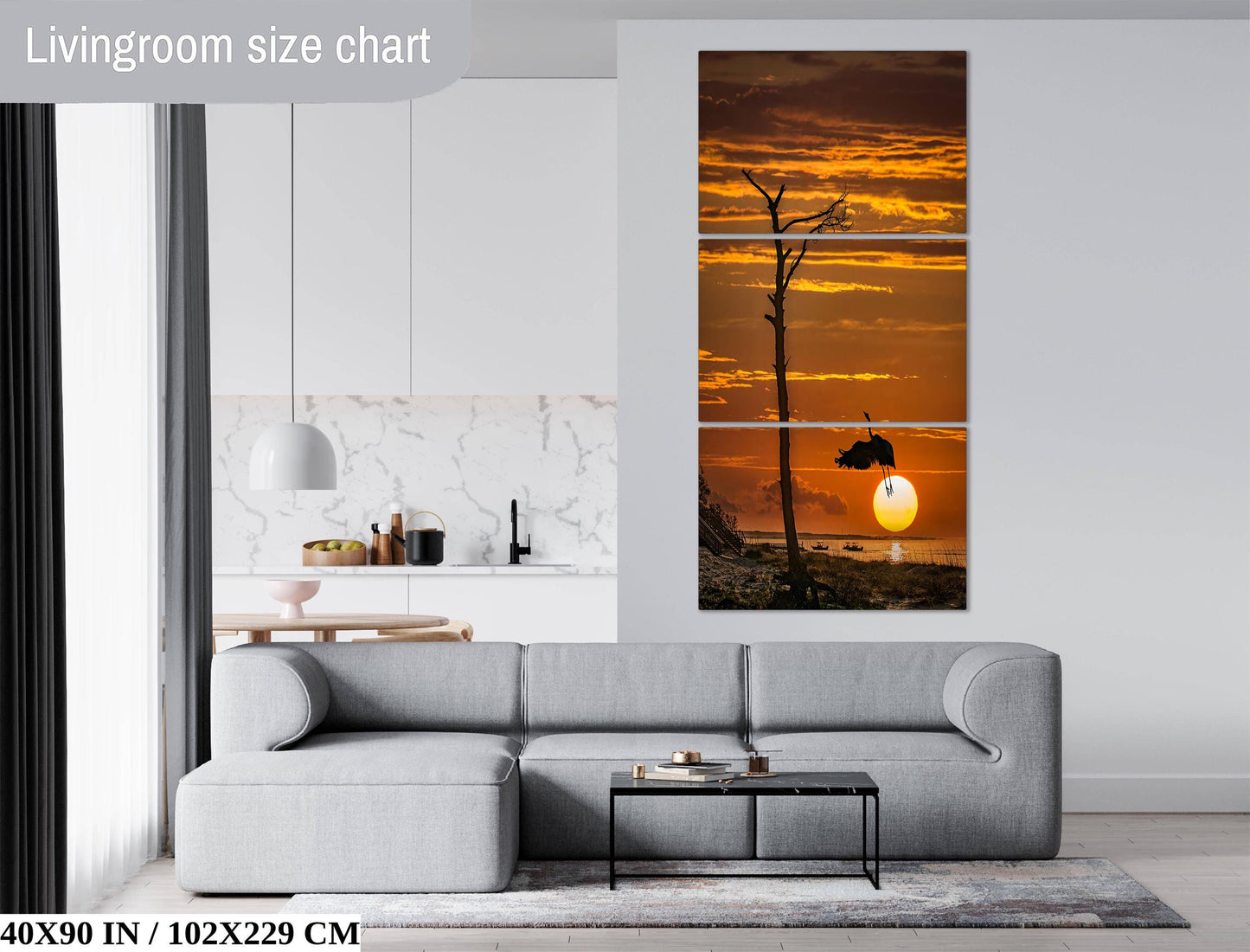 a living room with a gray sofa, a coffee table, and a large wall art depicting a sunset over a body of water.