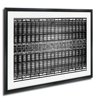 The image is a black and white photograph of a large, intricate metal structure with numerous interconnected beams and panels. The structure appears to be a complex architectural or industrial design, with a grid-like pattern of beams and panels covering the entire frame. The photograph is framed and hangs on a wall, showcasing the detailed and visually striking design.