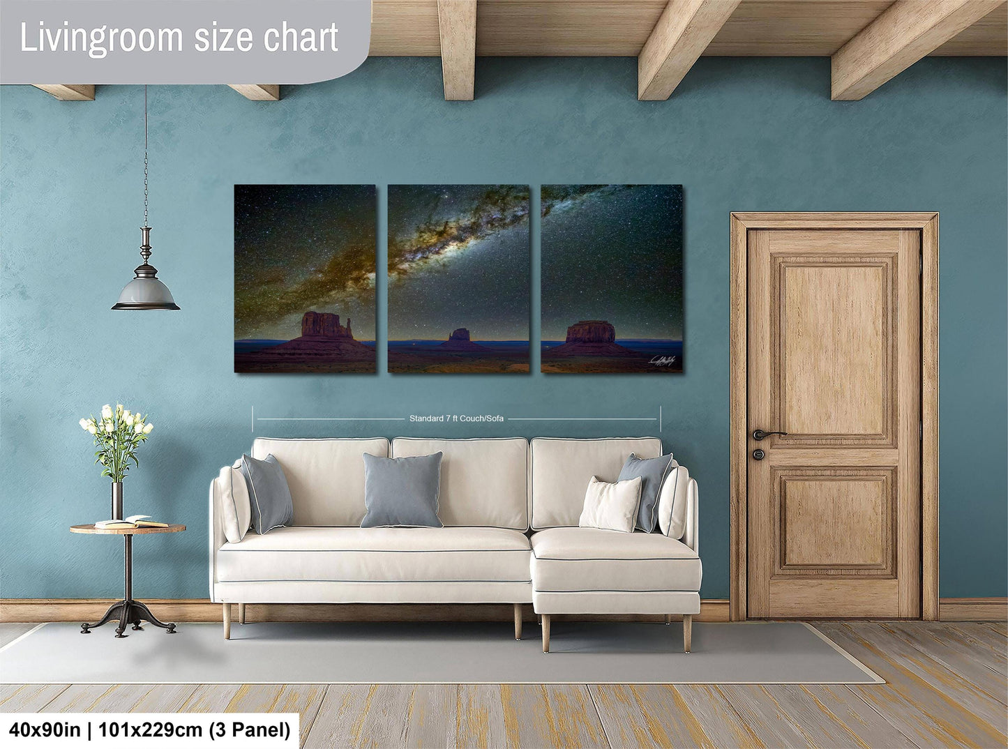 The image is a living room with a large white sofa, a wooden door, and a painting of a desert landscape on the wall.