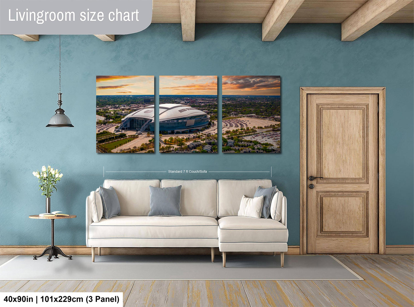 The image is a living room with a large wall art depicting a stadium. The wall art is divided into three panels, each showing different parts of the stadium. The living room has a white sofa and a wooden door.