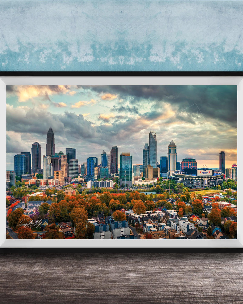 A framed aerial view of the skyline of a city, with tall buildings and skyscrapers against a cloudy sky.