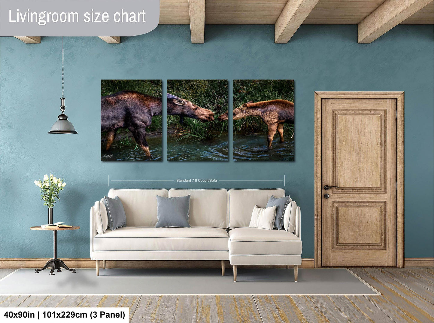 The image is a living room with a white sofa and a wooden door. Above the sofa, there is a wall-mounted living room size chart depicting three images of a moose in different poses.