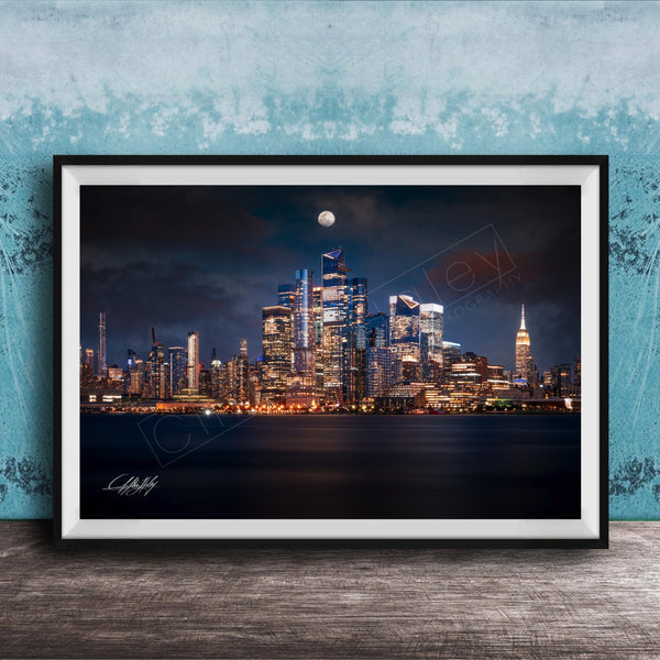 A framed photograph of the New York City skyline at night, with the city's iconic landmarks illuminated against a dark sky.