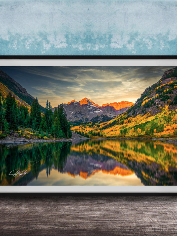 The image is a framed photograph depicting a serene mountain landscape with a lake reflecting the vibrant colors of the sunset.