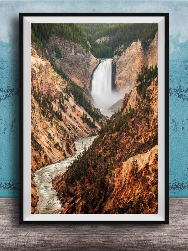 A framed photograph of a majestic waterfall cascading down a rugged, mountainous landscape.