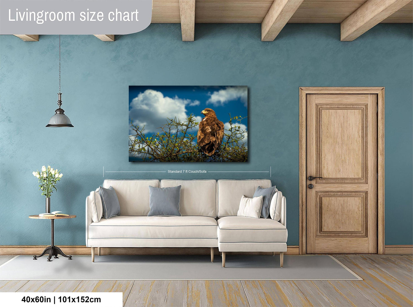 a living room with a large white sofa, a wooden door, and a painting of a bird perched on a branch.