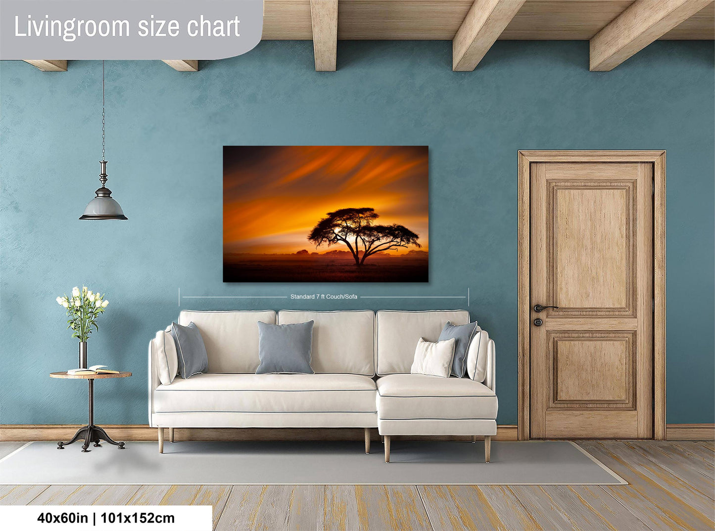 a living room with a large white sofa, a wooden door, and a painting of a tree with a sunset in the background.
