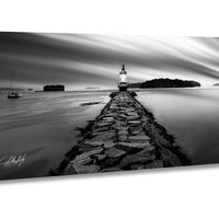 A black and white photograph depicting a lighthouse on a rocky pier extending into the water, with a small boat visible in the distance.