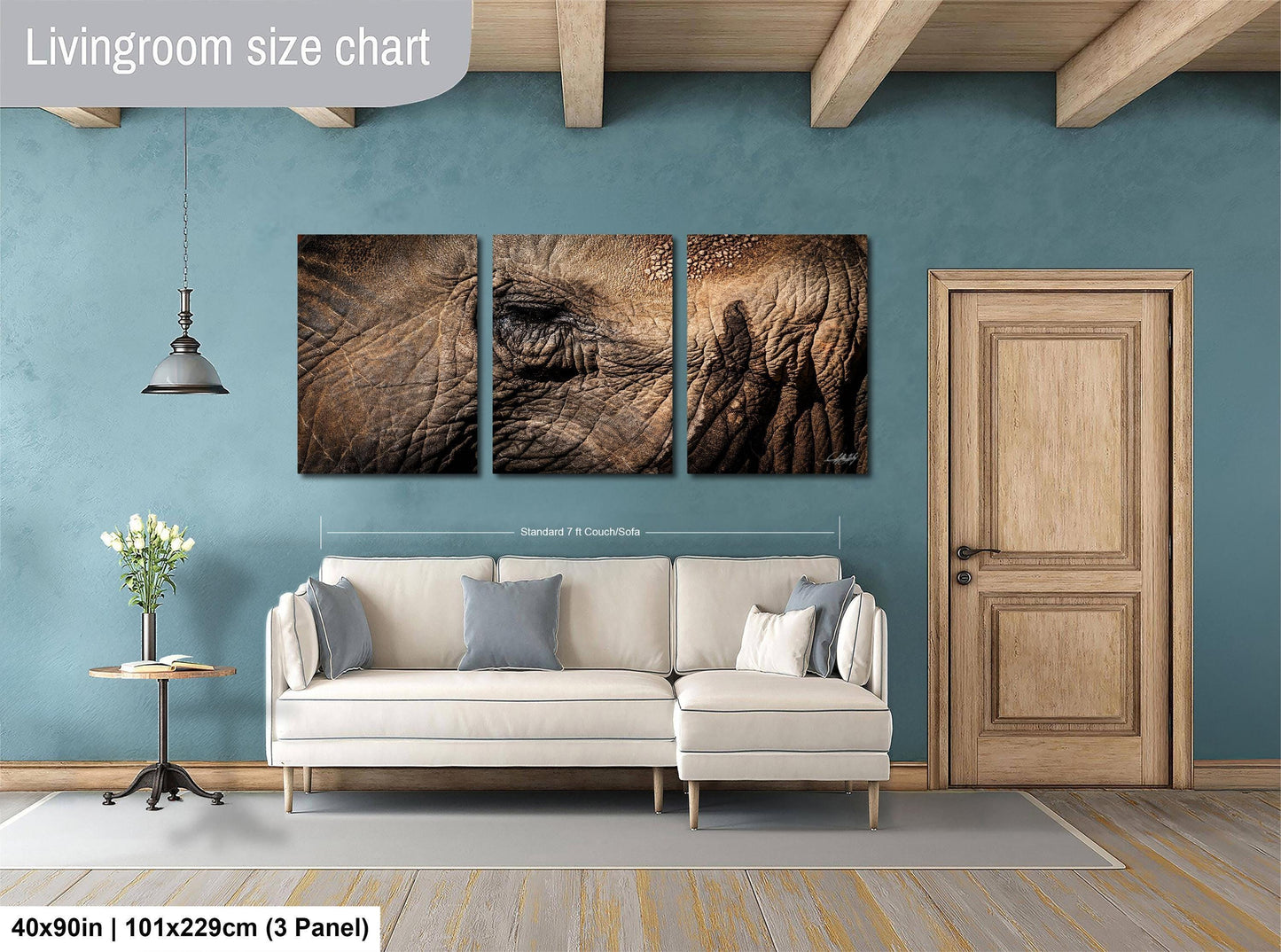 The image is a living room with a white sofa, a wooden door, and a wall with a large painting of an elephant.