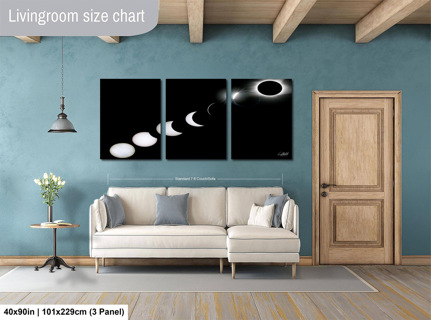 The image is a living room with a white sofa, a wooden door, and a wall with a large black and white solar eclipse painting.
