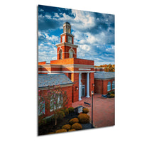 a red brick building with a prominent clock tower, set against a blue sky with white clouds.