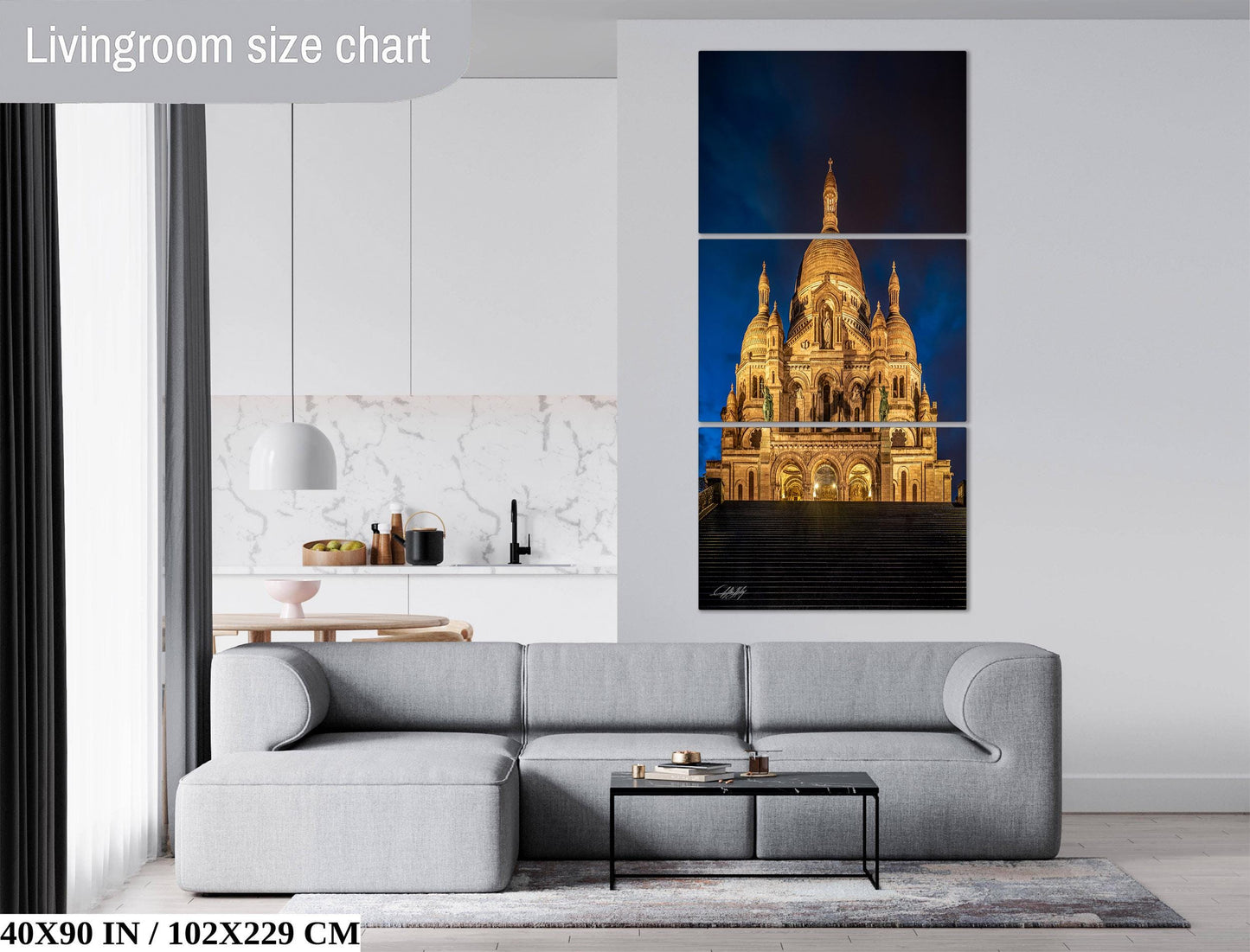 The image is a living room with a gray sofa, a coffee table, and a large wall art depicting a cathedral at night.