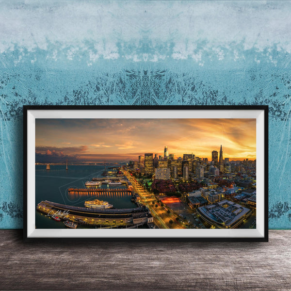The image is a framed photograph of a cityscape at sunset, featuring a skyline with tall buildings and a harbor with boats.