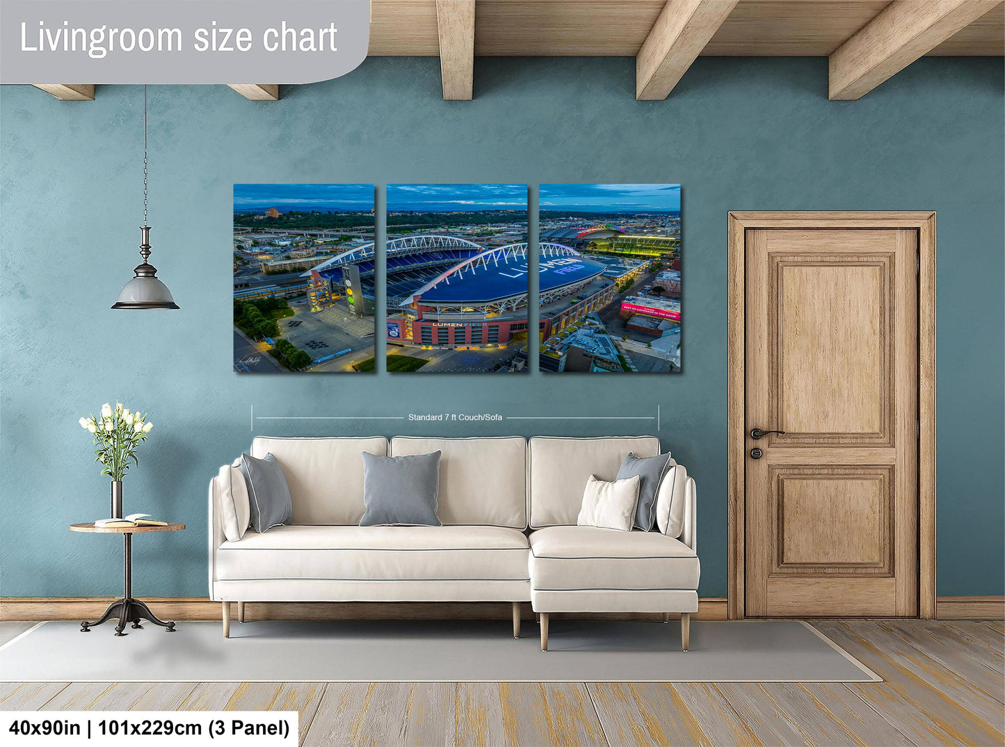 The image is a living room with a large wall art depicting a stadium. The wall art is divided into three panels, each showing different parts of the stadium. The living room has a white sofa and a wooden door.
