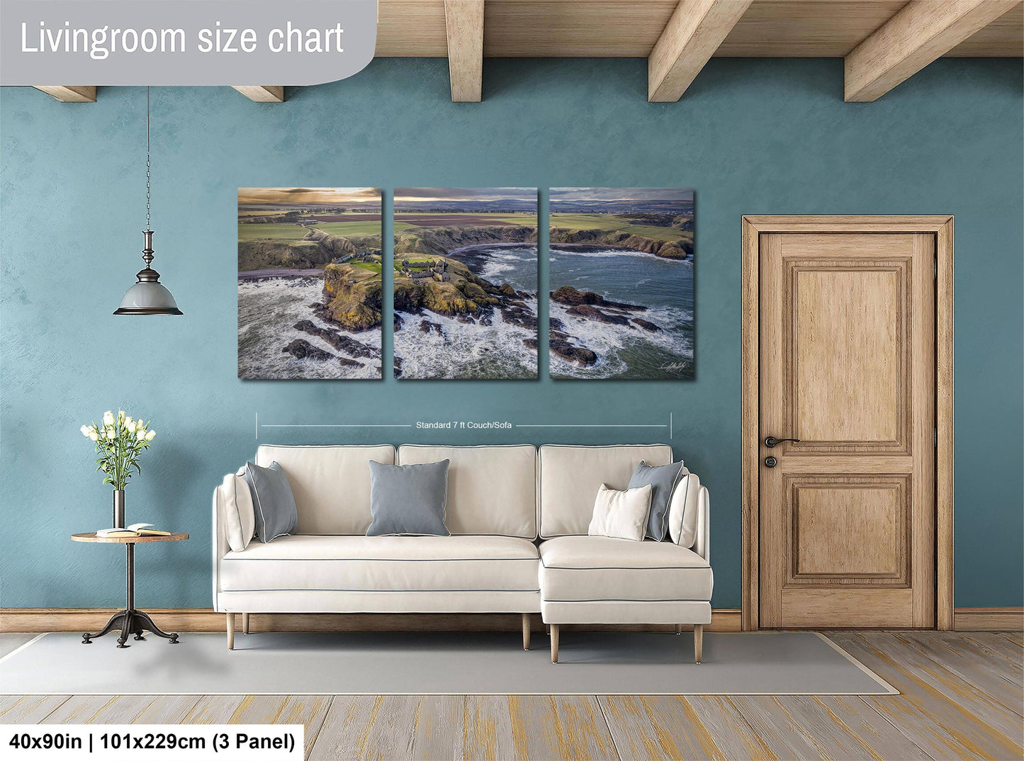 The image is a living room with a large, three-panel landscape painting hanging on the wall. The painting depicts a coastal scene with rocky cliffs, a body of water, and a sunset. The room has a white sofa and a wooden door, creating a cozy and inviting atmosphere.