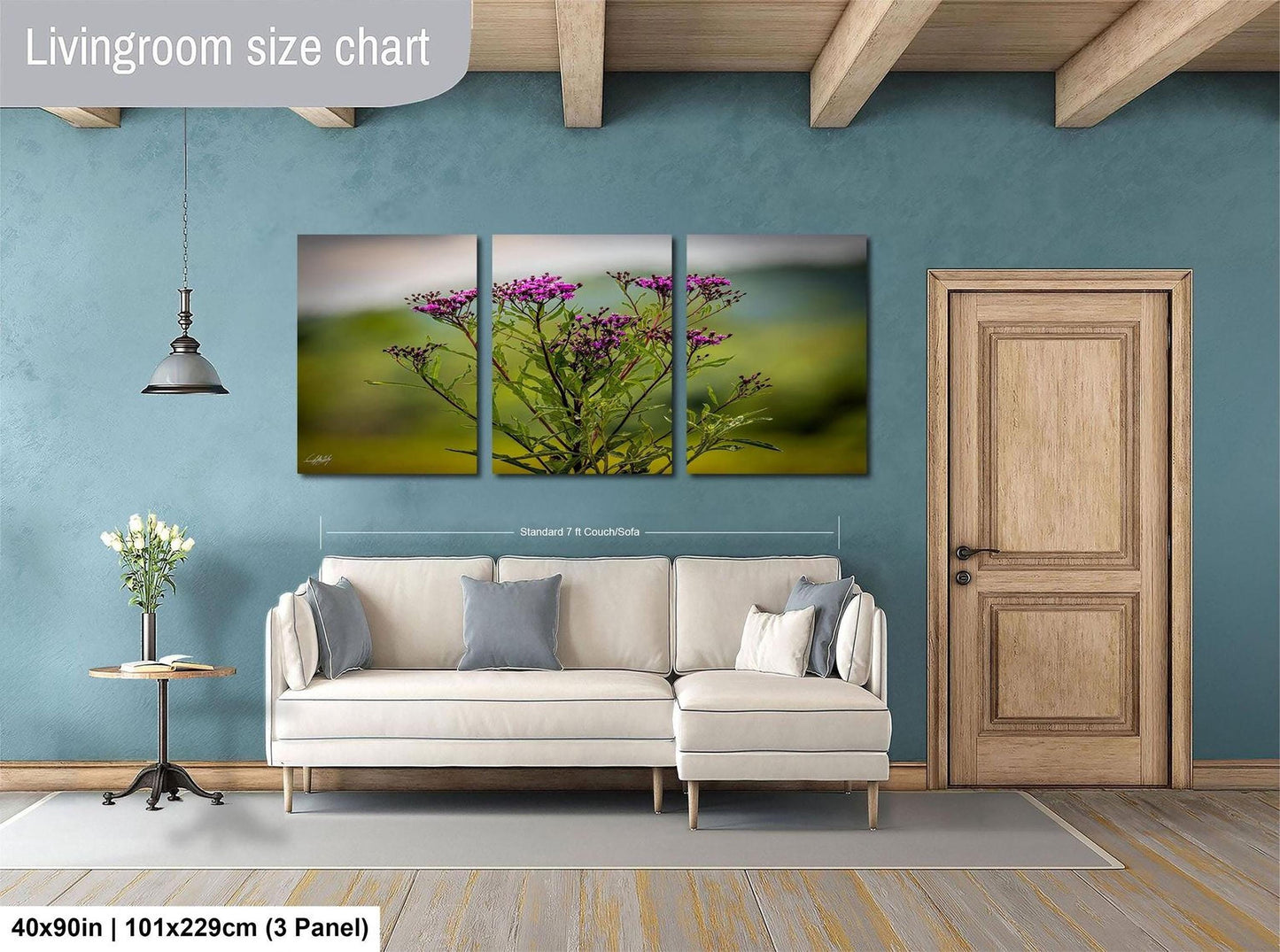 The image is a living room with a large white sofa, a wooden door, and a painting of a field of flowers hanging on the wall.