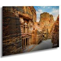a large, ancient stone structure carved into a cliff face, with a clear blue sky and a river flowing through the landscape.