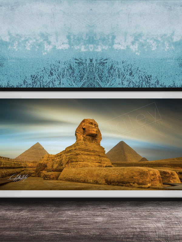 a framed photograph of the Great Sphinx of Giza, a large limestone statue of a mythical creature, in front of the pyramids of Giza in Egypt.