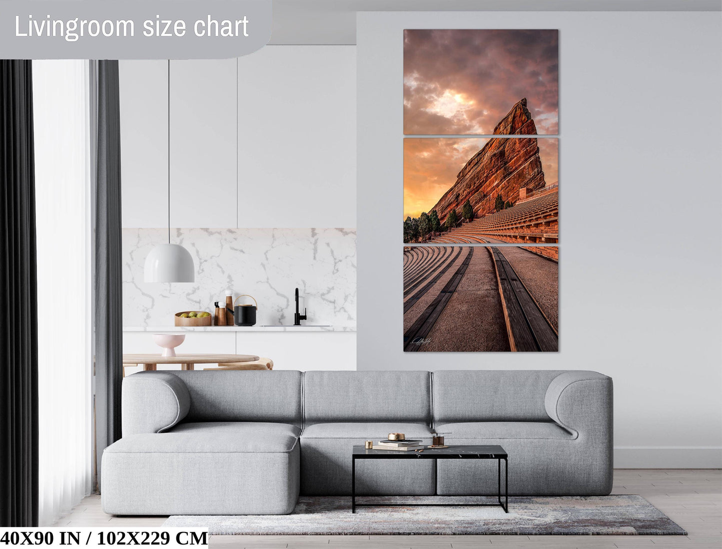 The image is a living room with a gray sofa, a coffee table, and a large wall art depicting a scenic view of a mountain range with a sunset.
