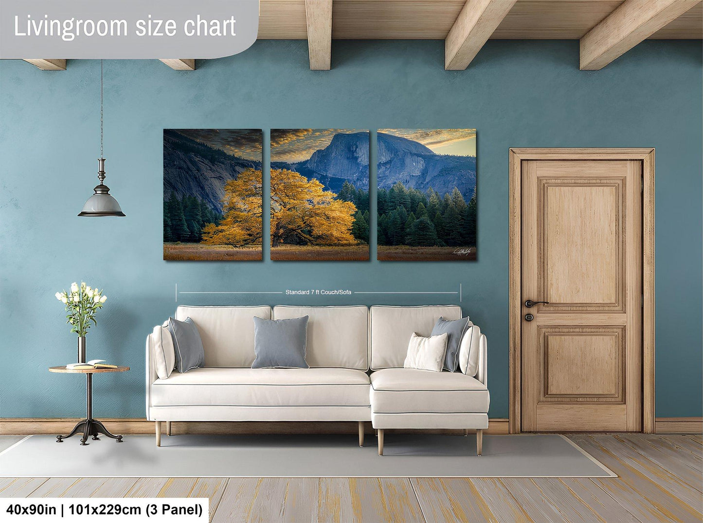 The image is a living room with a large white sofa, a wooden door, and a painting of a mountain landscape hanging on the wall.