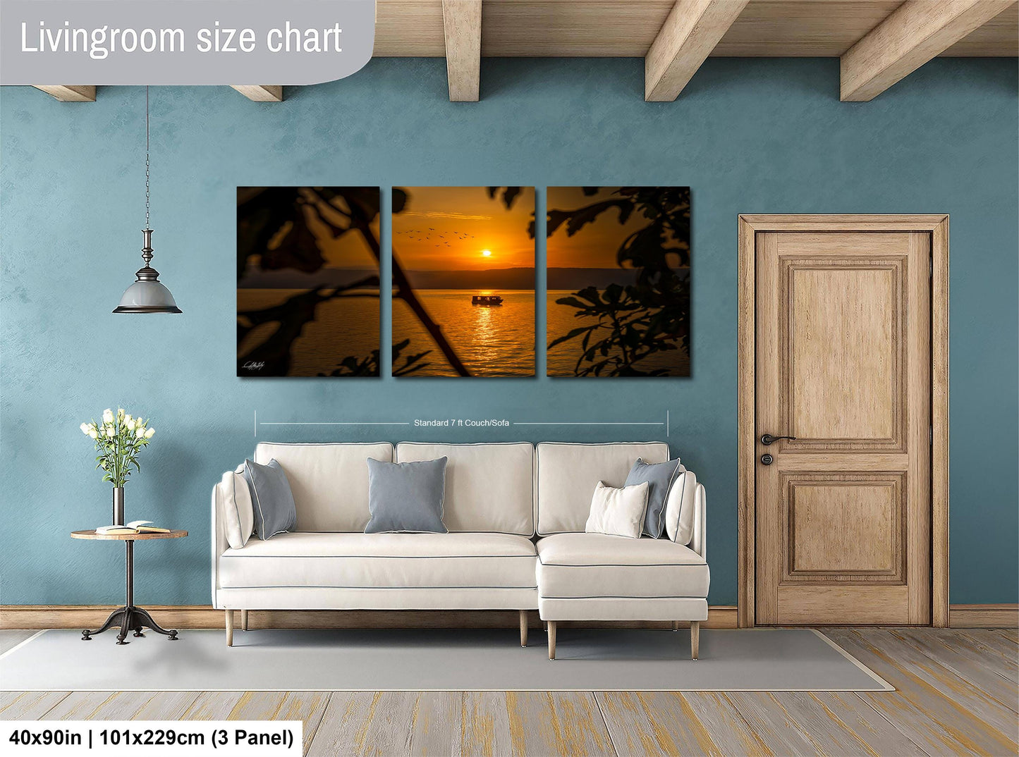 The image is a living room with a large wall art piece depicting a sunset over the ocean. The art piece is composed of three panels, each showing a different part of the sunset. The living room has a white sofa and a wooden door, creating a cozy and inviting atmosphere.