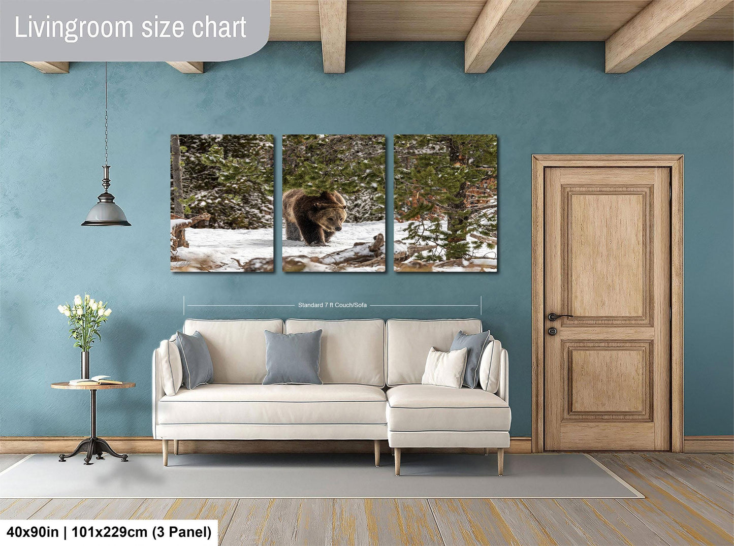 The image is a living room with a large wall art piece depicting a bear in a snowy forest. The wall art is divided into three panels, with the largest panel showing the bear and the other two smaller panels showing the forest. The living room has a white sofa and a wooden door, and the floor is covered with a gray rug.