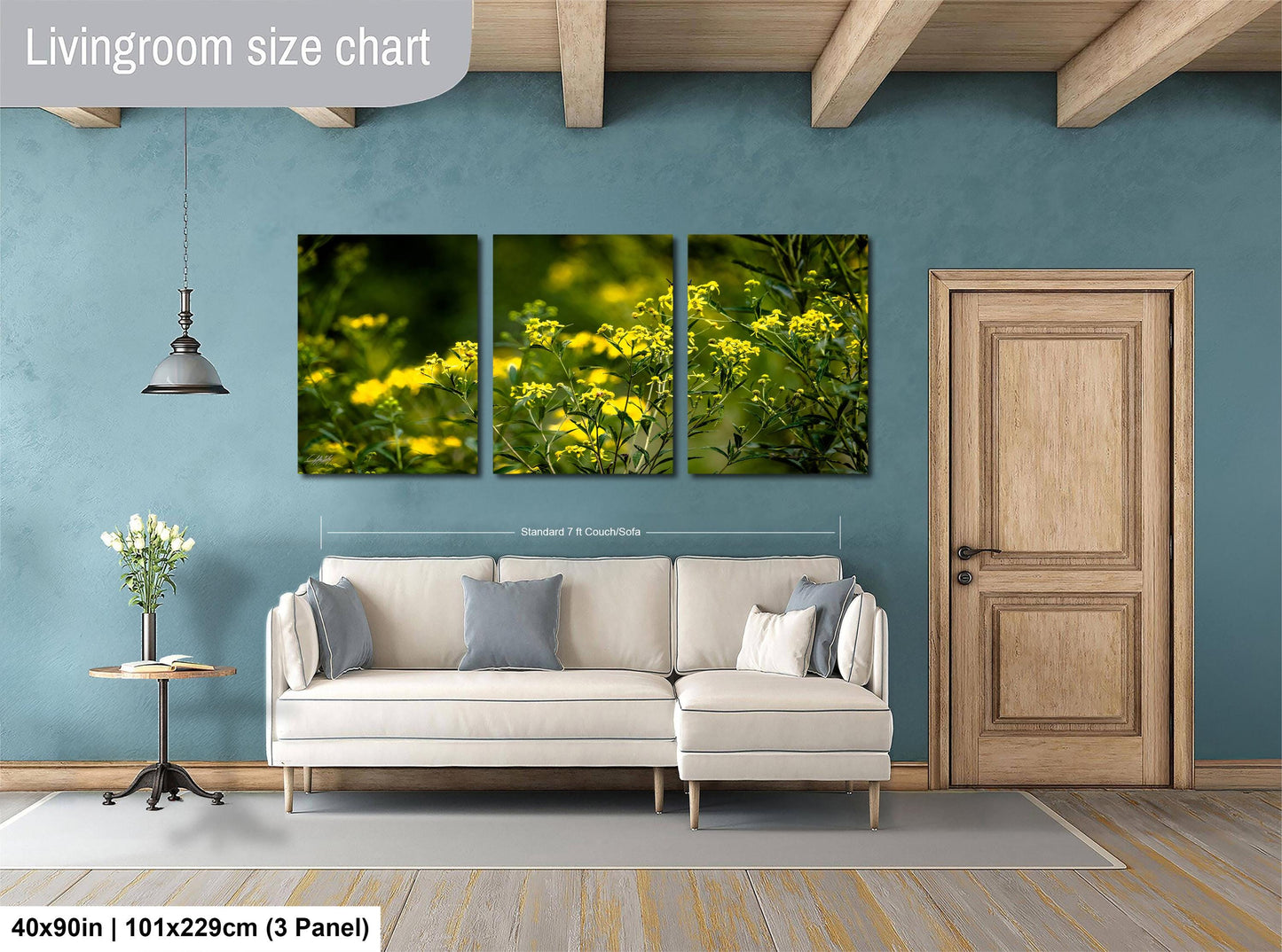 The image is a living room with a large living room size chart on the wall, a white sofa, a wooden door, and a small table with a vase of flowers.