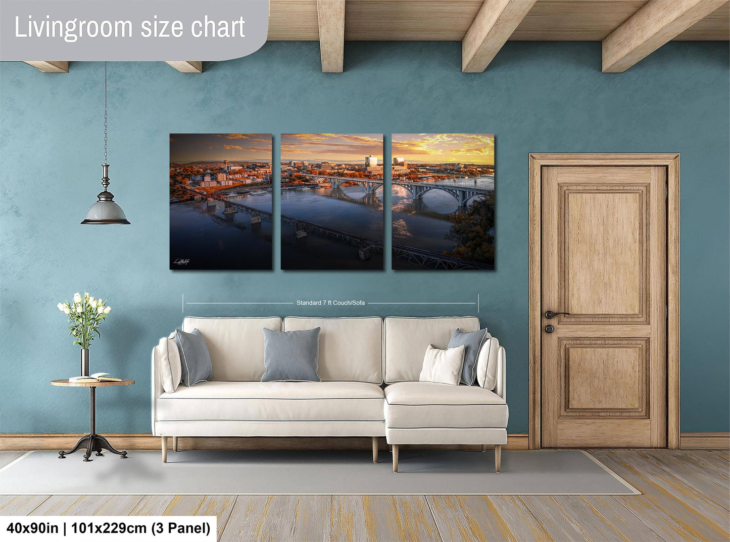 The image is a living room with a white sofa and a wooden door. Above the sofa, there is a triptych of pictures depicting a city skyline at sunset. The wall behind the sofa has a blue color, and the floor is covered with a gray rug.