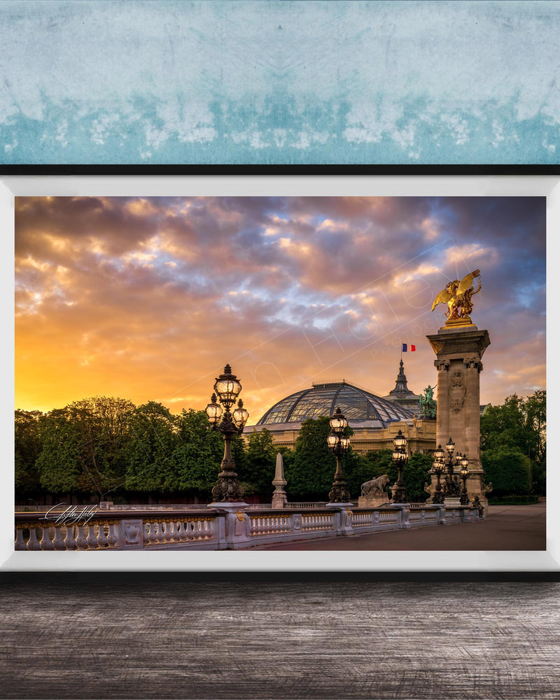 a picturesque scene of a cityscape with a large domed building, ornate lampposts, and a statue of a winged figure, all set against a vibrant sunset sky.
