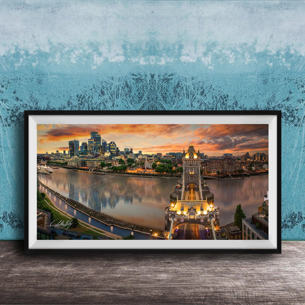 A framed photograph of the skyline of a city at sunset, with the city's iconic landmarks and buildings illuminated against a colorful sky.