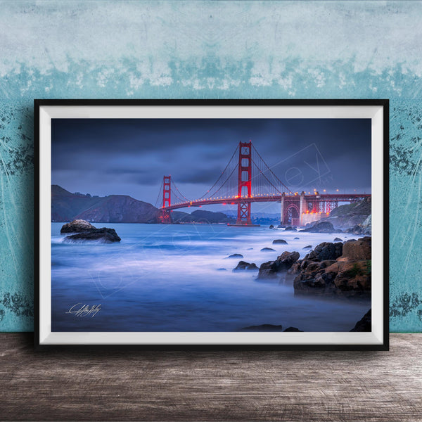 A framed photograph of the Golden Gate Bridge at night, with the bridge illuminated against a dark sky and the ocean in the foreground.