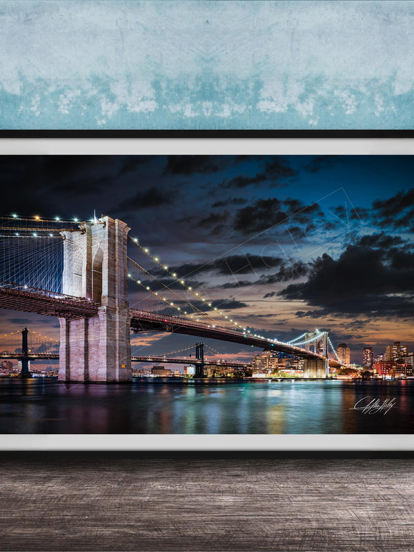 A framed photograph of the Brooklyn Bridge at night, with its iconic towers and suspension cables illuminated against a dark sky.