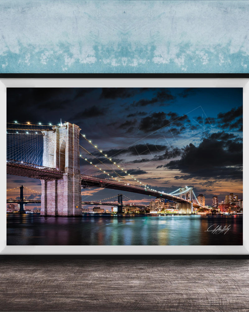 A framed photograph of the Brooklyn Bridge at night, with its iconic towers and suspension cables illuminated against a dark sky.
