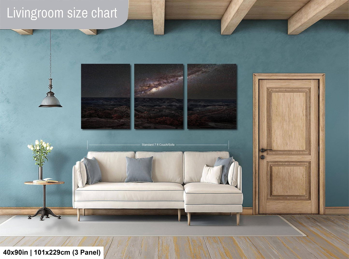 The image is a living room with a white sofa, a wooden door, and a large wall art depicting a night sky with a galaxy.