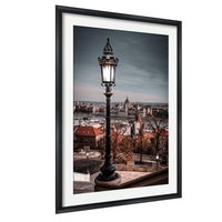 a cityscape with a tall, ornate street lamp in the foreground, overlooking the city below.