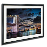 A framed photograph of the Brooklyn Bridge at night, with the bridge illuminated and the city skyline visible in the background.