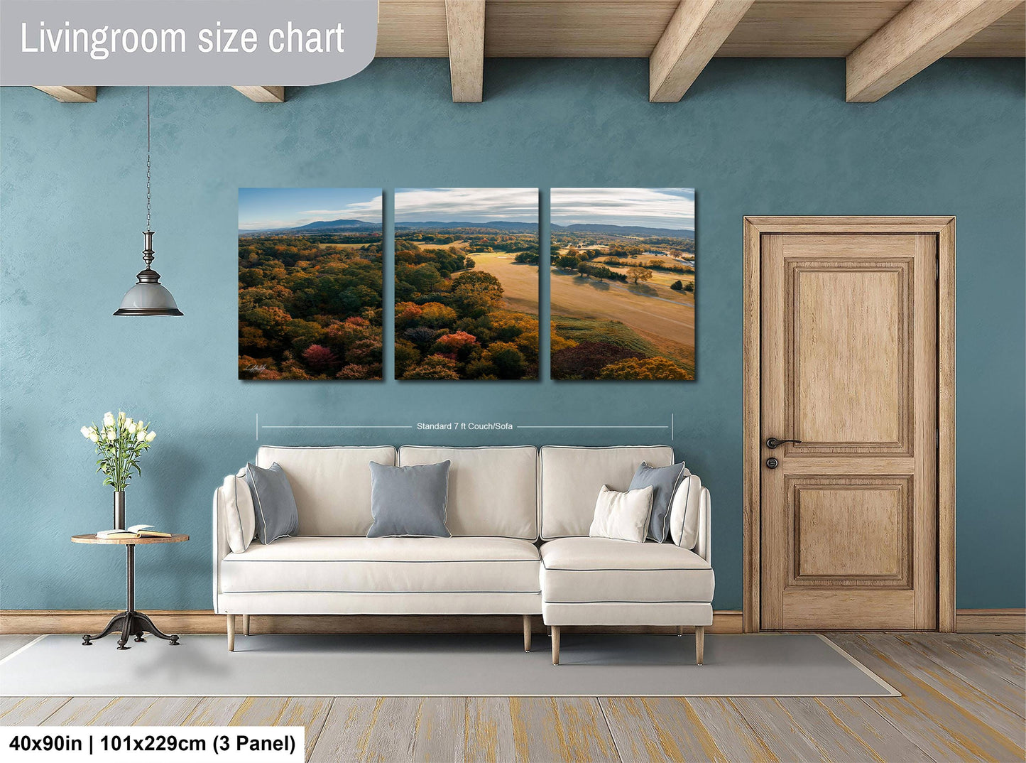 The image is a living room with a large wall art depicting a scenic landscape with trees and a field. The living room has a white sofa and a wooden door.