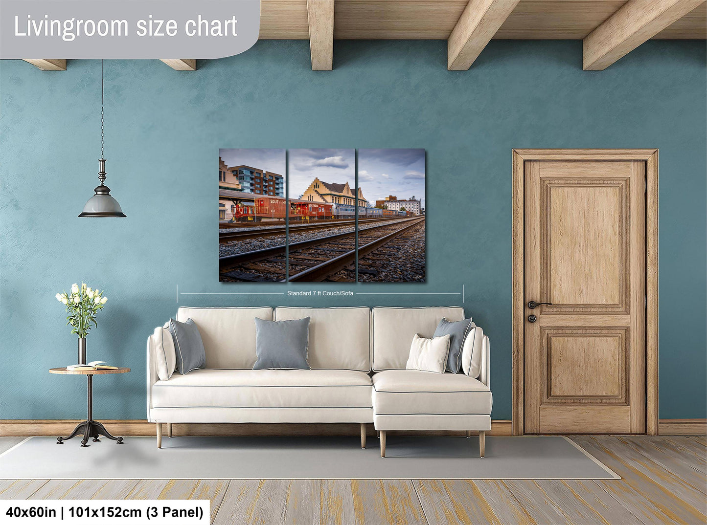 The image is a living room with a white sofa, a wooden door, and a large wall art depicting a train on the tracks.